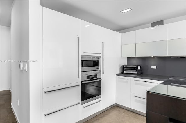 kitchen featuring appliances with stainless steel finishes, decorative backsplash, and white cabinets