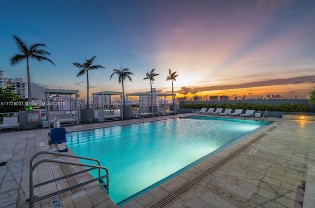 pool at dusk featuring a patio area