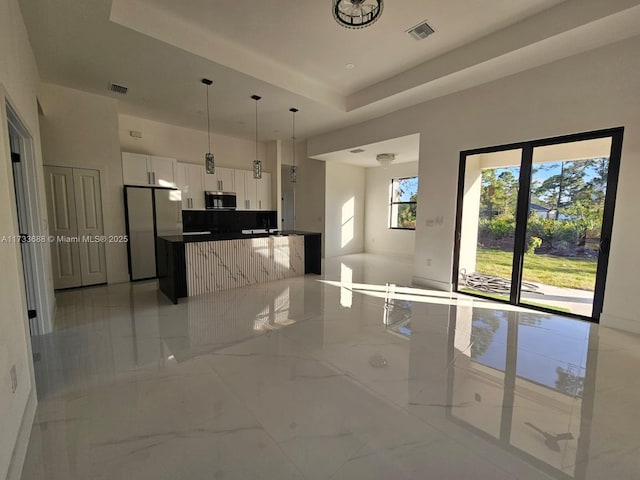 kitchen with white cabinetry, stainless steel appliances, decorative light fixtures, and a raised ceiling