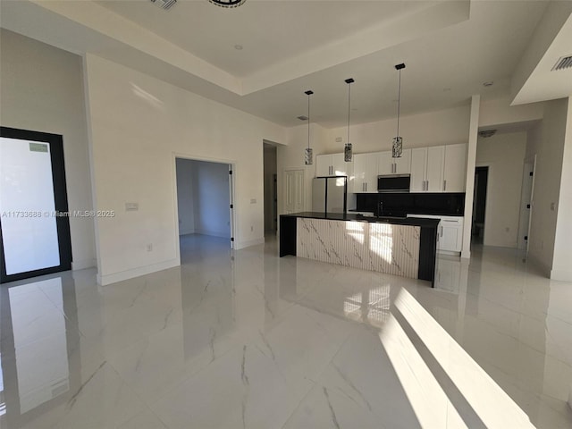 kitchen featuring white cabinetry, hanging light fixtures, appliances with stainless steel finishes, a kitchen island, and a high ceiling