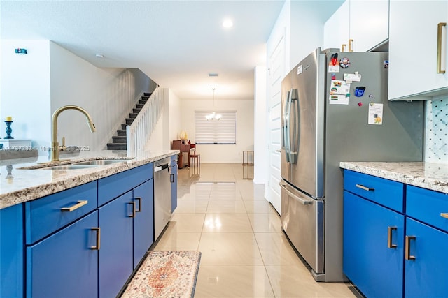 kitchen with pendant lighting, sink, light stone counters, white cabinets, and blue cabinets