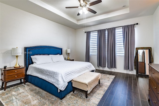 bedroom with dark hardwood / wood-style floors, a raised ceiling, and ceiling fan