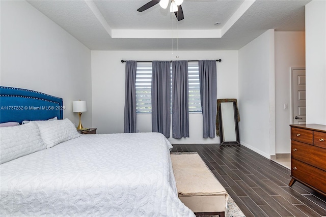 bedroom with ceiling fan, a raised ceiling, and a textured ceiling