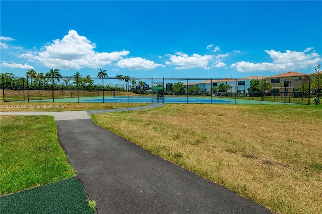 view of property's community with tennis court and a lawn