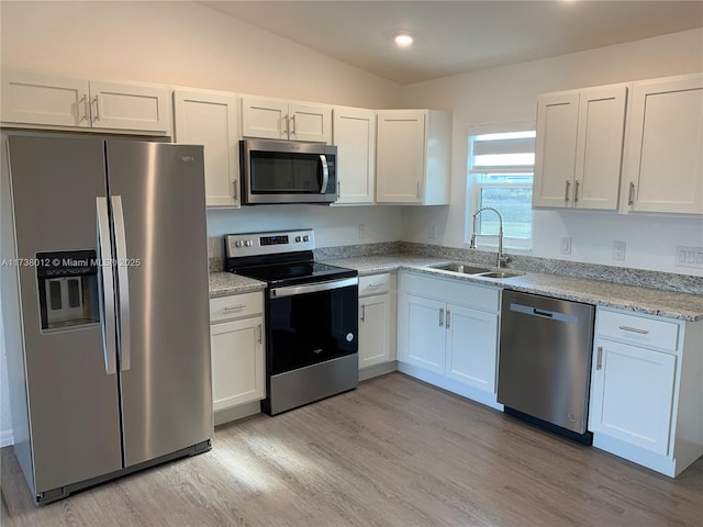 kitchen with stainless steel appliances, sink, white cabinets, and light stone counters