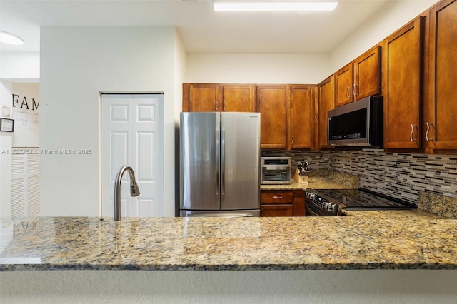 kitchen featuring stainless steel appliances, tasteful backsplash, light stone countertops, and kitchen peninsula