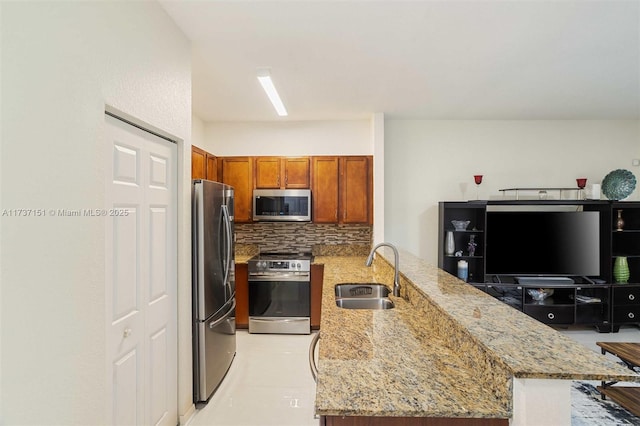 kitchen featuring sink, light stone countertops, kitchen peninsula, and appliances with stainless steel finishes