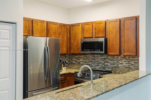 kitchen with light stone counters, appliances with stainless steel finishes, and backsplash