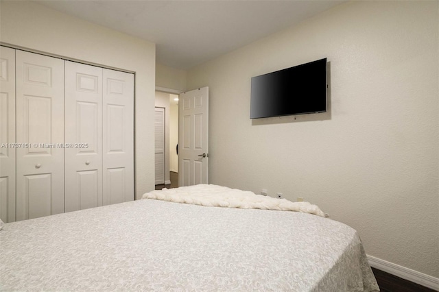 bedroom with dark hardwood / wood-style floors and a closet