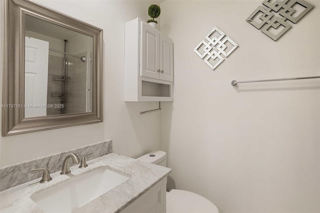 bathroom with vanity, toilet, and tiled shower