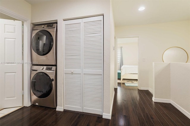 laundry room featuring dark hardwood / wood-style floors and stacked washer and clothes dryer