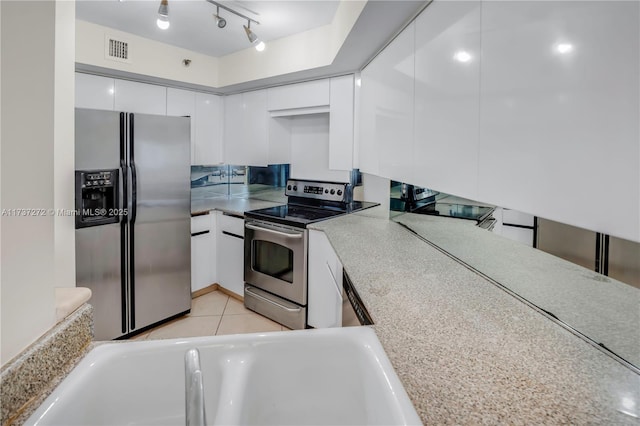 kitchen featuring appliances with stainless steel finishes, sink, light tile patterned floors, and white cabinets