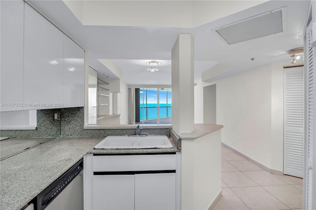 kitchen featuring light tile patterned flooring, sink, white cabinetry, dishwasher, and decorative backsplash