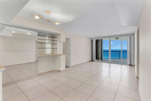 tiled spare room with floor to ceiling windows and a water view