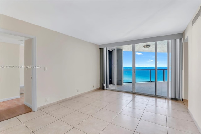 tiled spare room featuring expansive windows and a water view