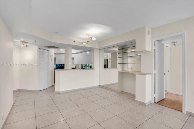 kitchen with kitchen peninsula, light tile patterned floors, and white cabinets