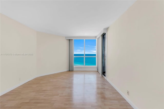 empty room featuring a water view and light wood-type flooring