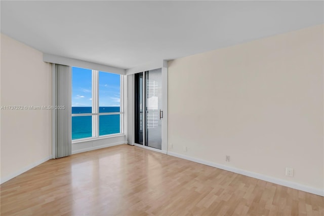 spare room featuring a water view and light wood-type flooring