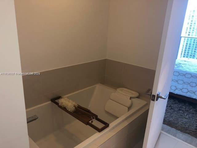 bathroom with a relaxing tiled tub and tile patterned flooring