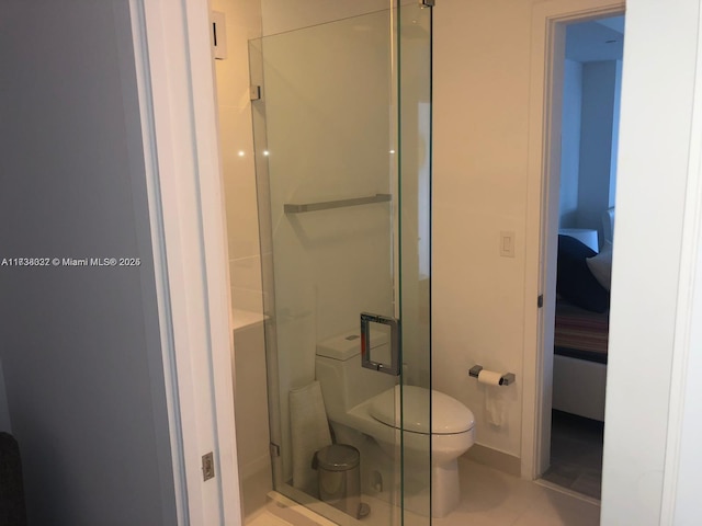 bathroom with a shower with shower door, tile patterned floors, and toilet