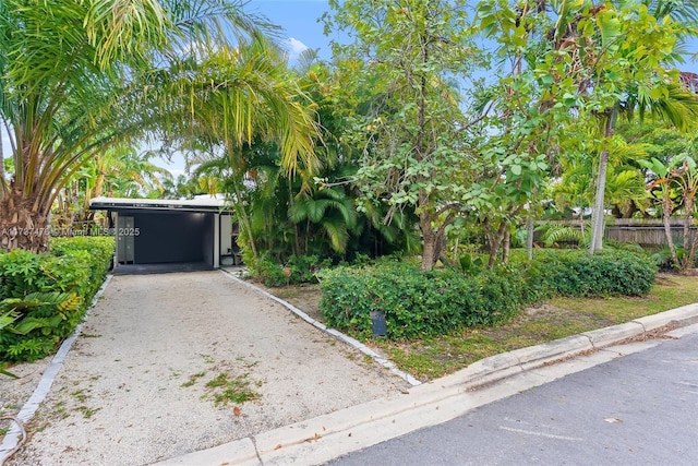 exterior space with a carport, gravel driveway, and fence