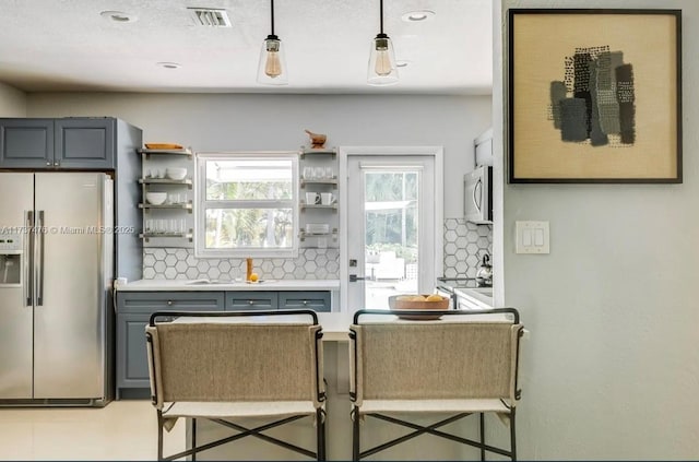 kitchen featuring gray cabinetry, stainless steel appliances, visible vents, backsplash, and open shelves