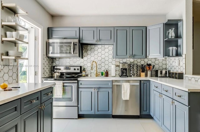 kitchen with tasteful backsplash, appliances with stainless steel finishes, open shelves, and light countertops