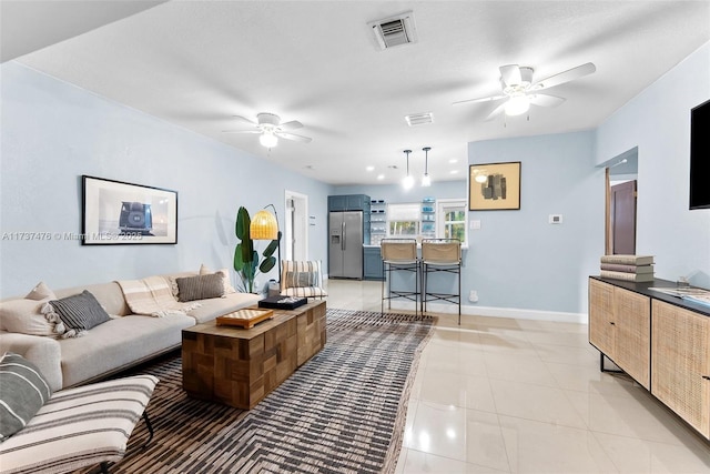 living area with light tile patterned floors, baseboards, visible vents, and a ceiling fan