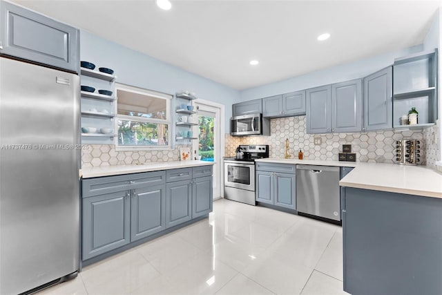 kitchen with open shelves, tasteful backsplash, light countertops, gray cabinetry, and appliances with stainless steel finishes