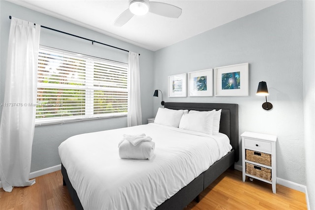 bedroom featuring a ceiling fan, baseboards, and wood finished floors