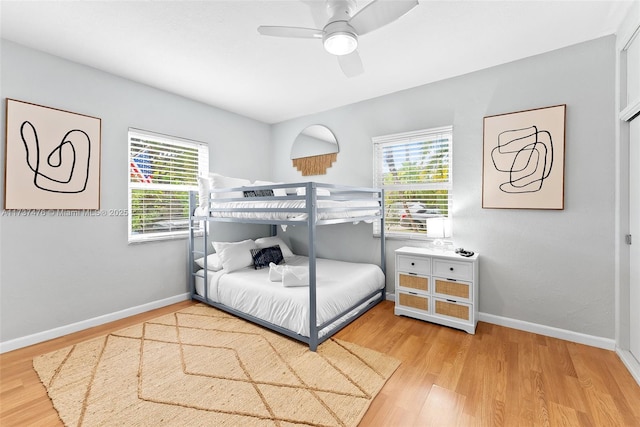 bedroom with ceiling fan, multiple windows, wood finished floors, and baseboards