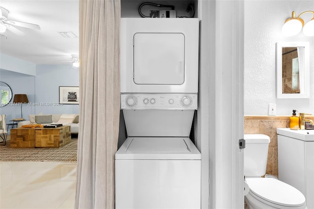 laundry room featuring stacked washing maching and dryer, ceiling fan, visible vents, and laundry area