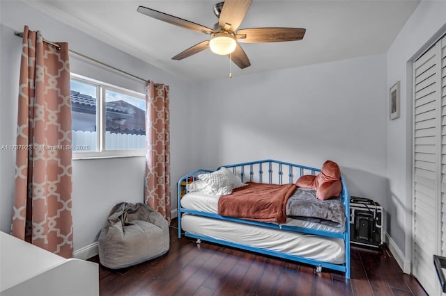 bedroom with dark wood-type flooring, ceiling fan, and a closet