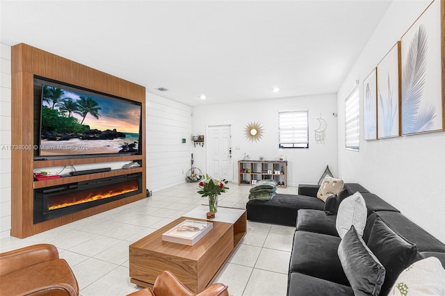 living area featuring recessed lighting, visible vents, light tile patterned flooring, and a glass covered fireplace