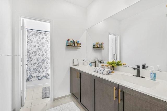 bathroom with shower / tub combo with curtain, double vanity, a sink, baseboards, and tile patterned floors