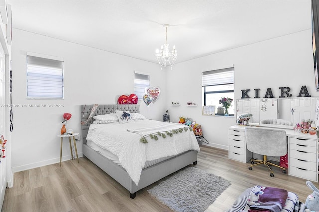 bedroom featuring baseboards, light wood finished floors, and an inviting chandelier