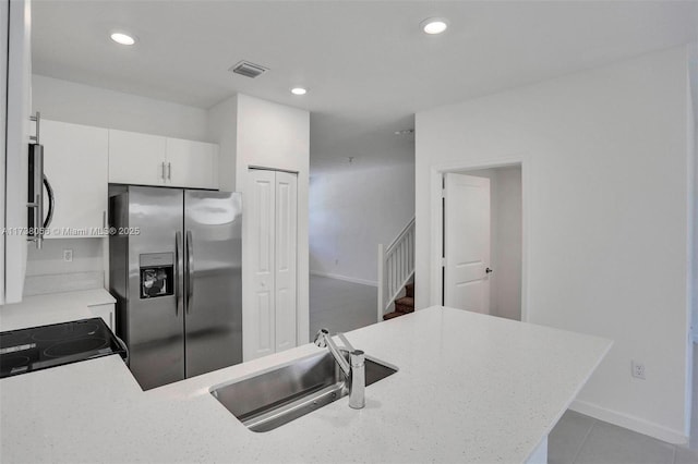 kitchen featuring light tile patterned flooring, appliances with stainless steel finishes, white cabinetry, sink, and kitchen peninsula