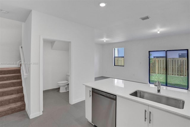 kitchen featuring light tile patterned floors, dishwasher, sink, and white cabinets