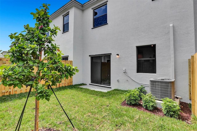 rear view of property featuring cooling unit and a lawn