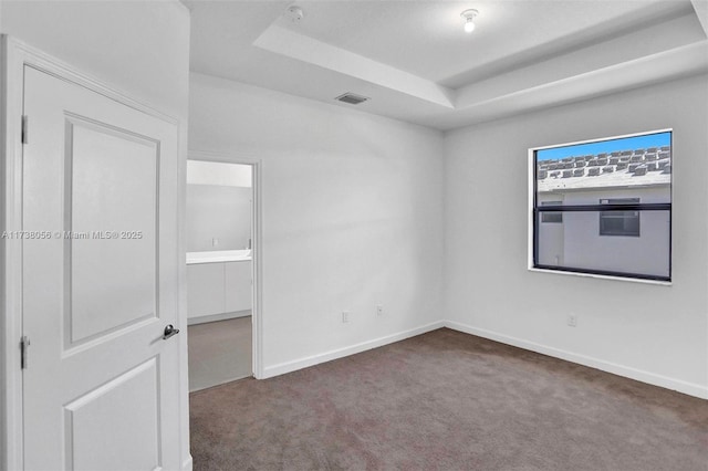 carpeted empty room featuring a tray ceiling