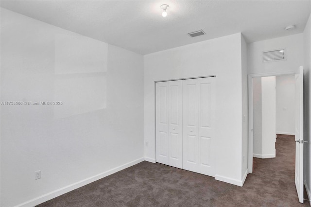 unfurnished bedroom featuring dark carpet and a closet