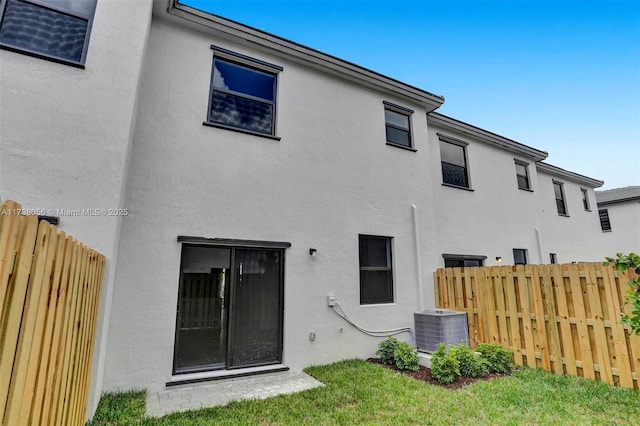 back of property with a yard and central air condition unit