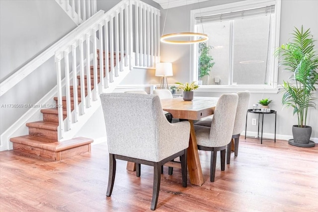 dining area with baseboards, wood finished floors, and stairway