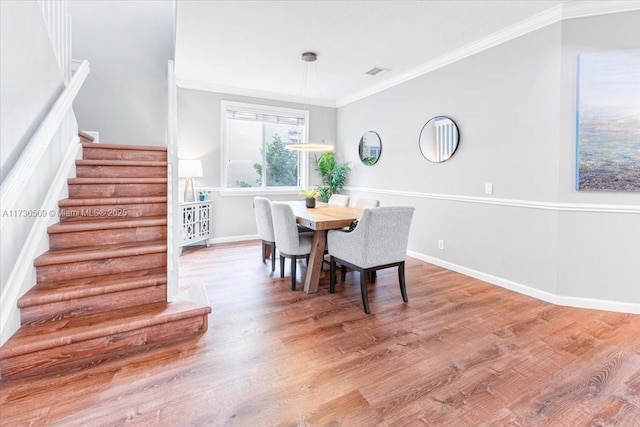 dining space with visible vents, crown molding, wood finished floors, baseboards, and stairway