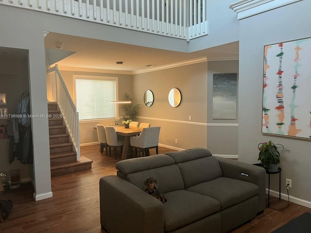 living room featuring hardwood / wood-style flooring, ornamental molding, and a towering ceiling