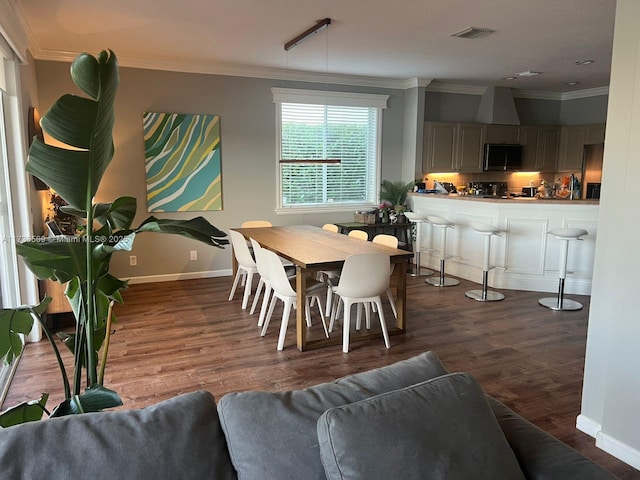 dining area with ornamental molding and dark hardwood / wood-style flooring