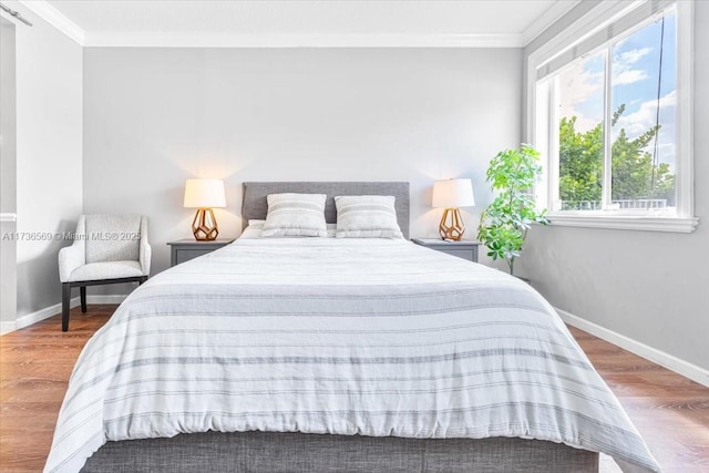 bedroom featuring baseboards, ornamental molding, and wood finished floors