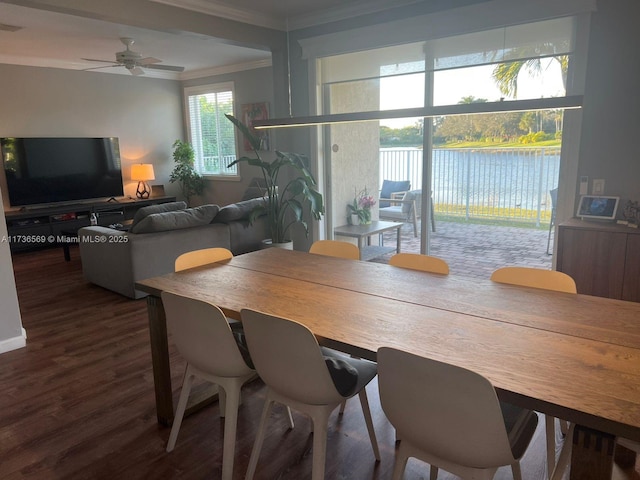 dining space featuring ornamental molding, a water view, dark wood-type flooring, and ceiling fan