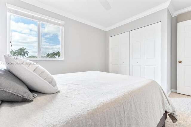 carpeted bedroom featuring a closet, ornamental molding, baseboards, and a ceiling fan