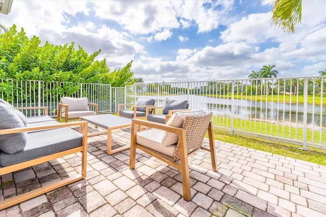view of patio featuring a water view, outdoor lounge area, and fence